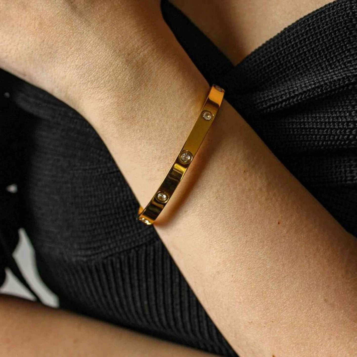 Gold minimalist love cuff bracelet worn on wrist, showcasing its elegant and polished design with sparkling zirconia stones.