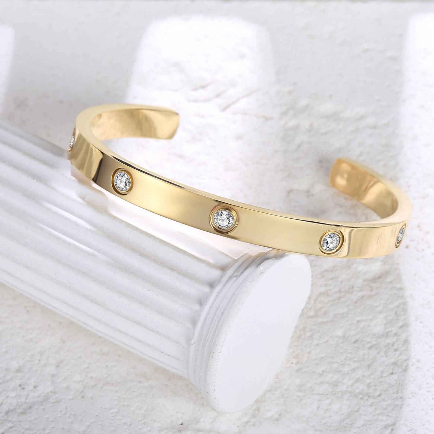 Angled view of gold minimalist love cuff bracelet with zirconia stones, emphasizing its elegant and durable design.