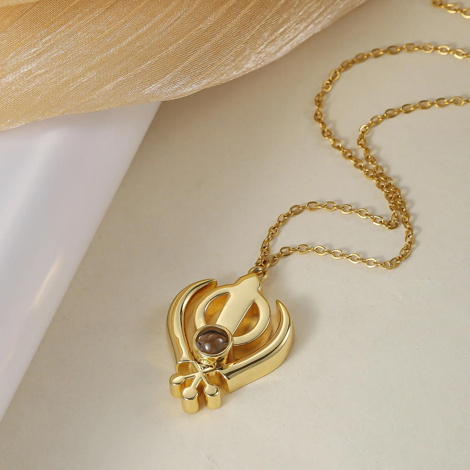 Close-up of gold 3D Khanda Pendant Necklace with a central projection stone, highlighting its intricate Sikh design.