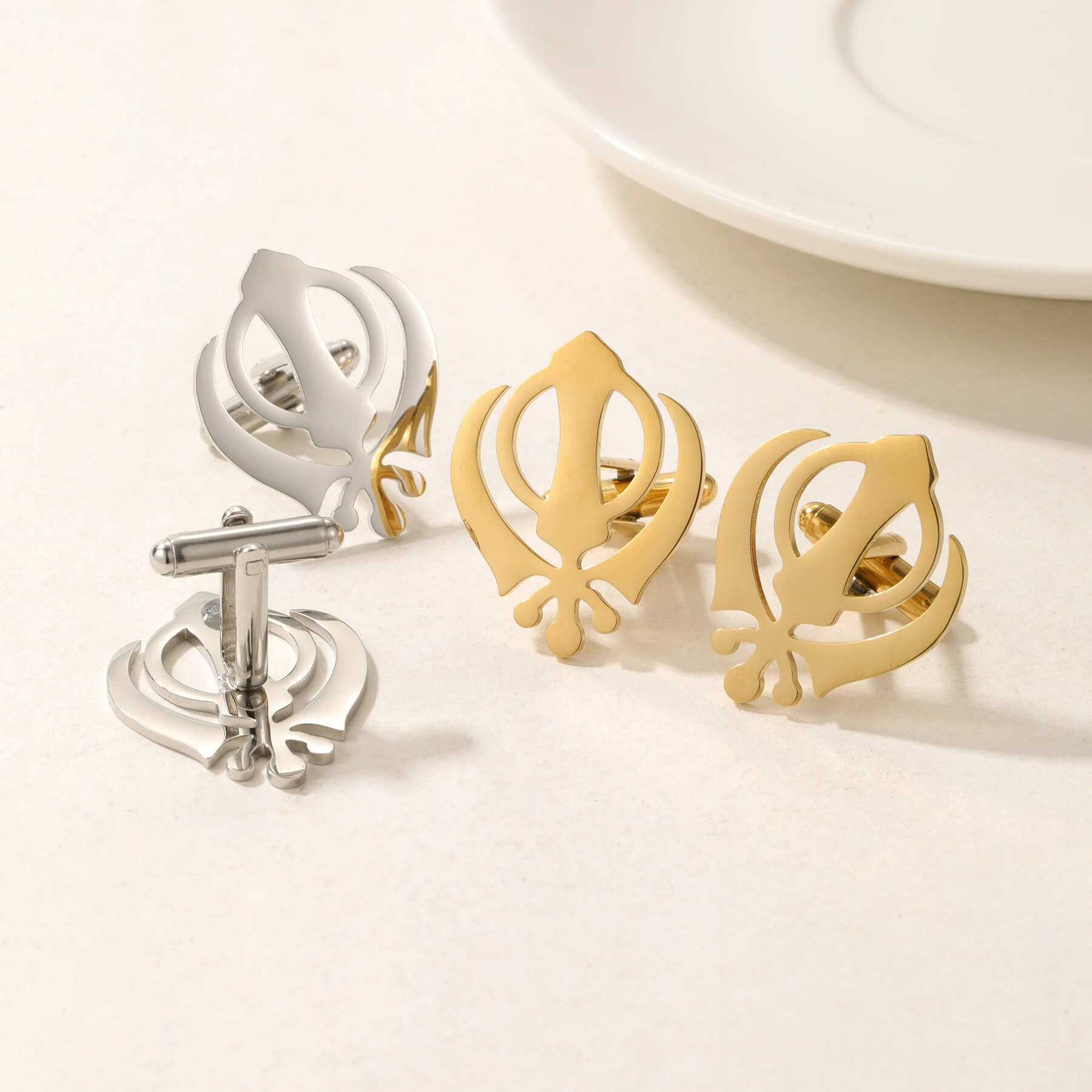 Set of Punjabi Sikh cufflinks in gold and silver stainless steel with Khanda symbol, displayed on a neutral background.