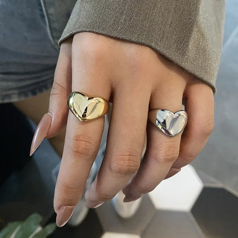 Two heart-shaped rings on fingers: one gold and one silver, showcasing elegance and vintage charm.