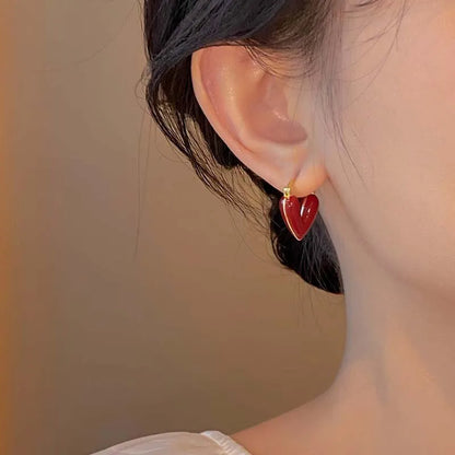 Red enamel heart hoop earrings displayed on a model, showcasing vintage-inspired elegance and style.