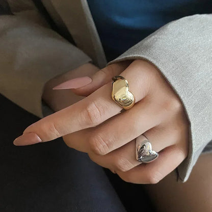 Elegant hand wearing Lustrous Heart Rings in gold and silver, showcasing vintage-inspired charm and adjustable fit.