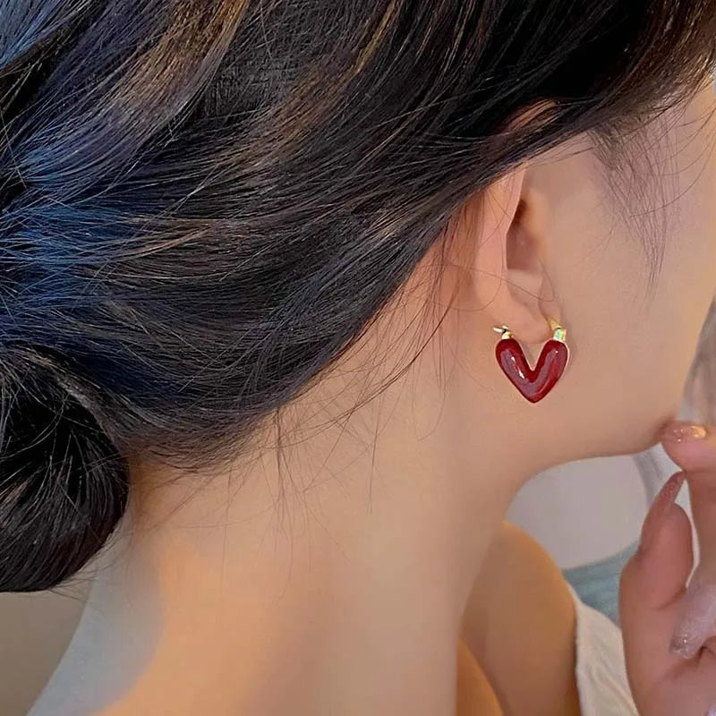 Antique Love Hearts Hoops featuring red enamel heart charms on sleek metal hoops worn in an elegant hairstyle.