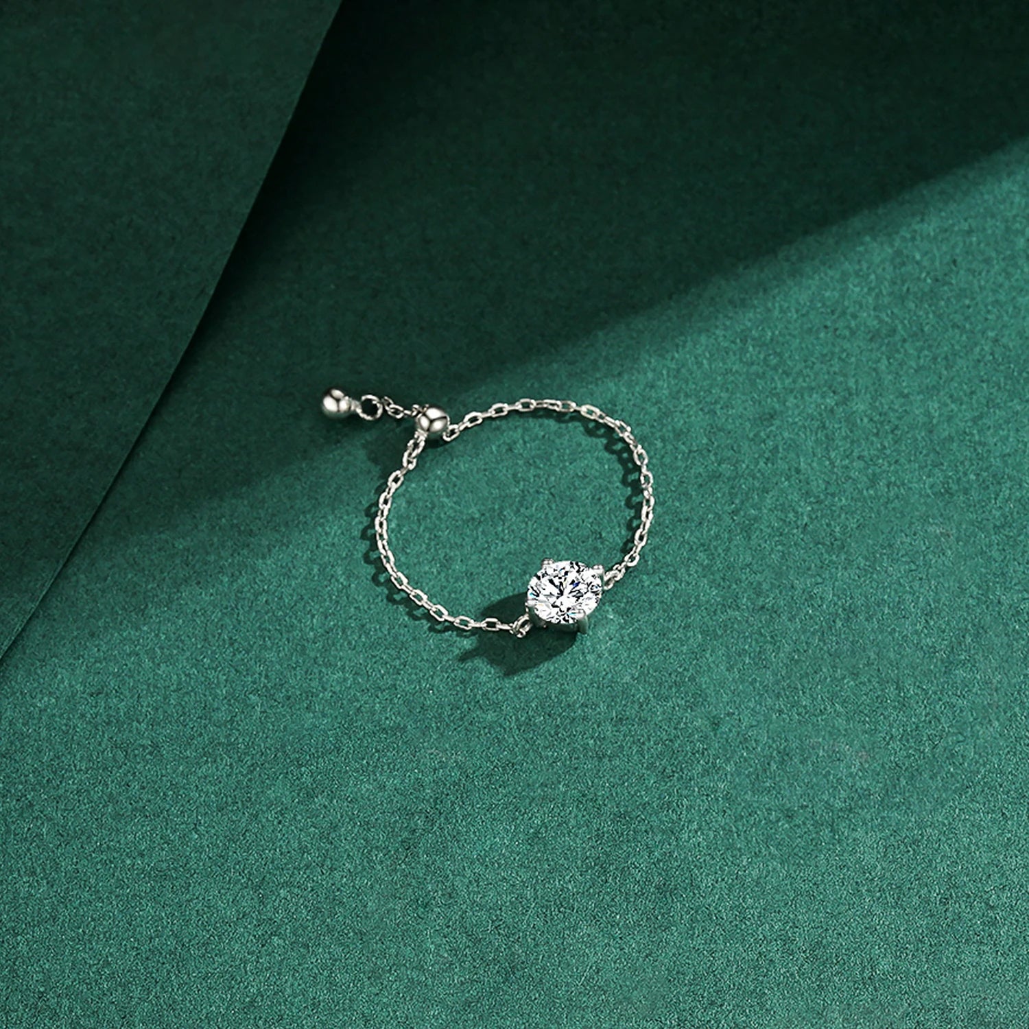 The Original Self-Love Chain Ring in 925 sterling silver with a sparkling round zircon on a green background.