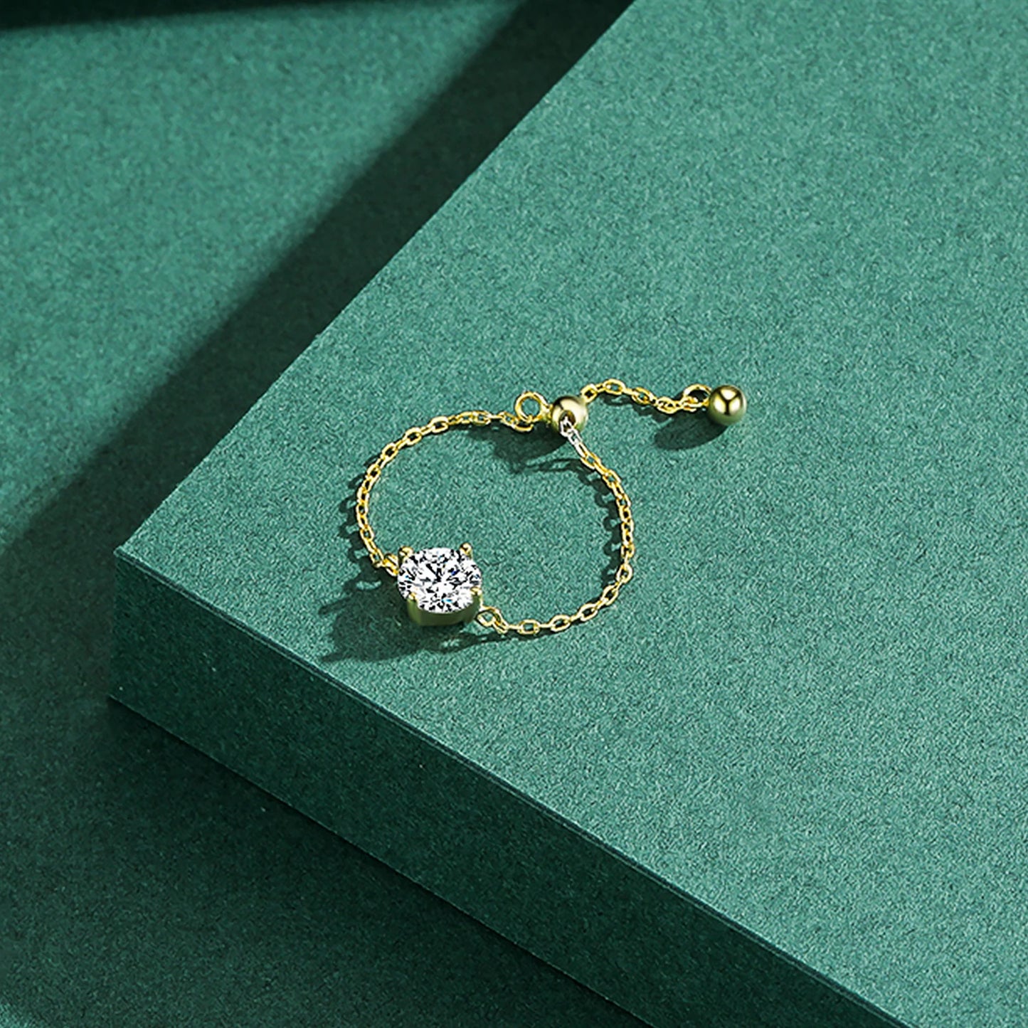 The Original Self-Love Chain Ring with round zircon in 925 sterling silver, showcased on a textured green background.