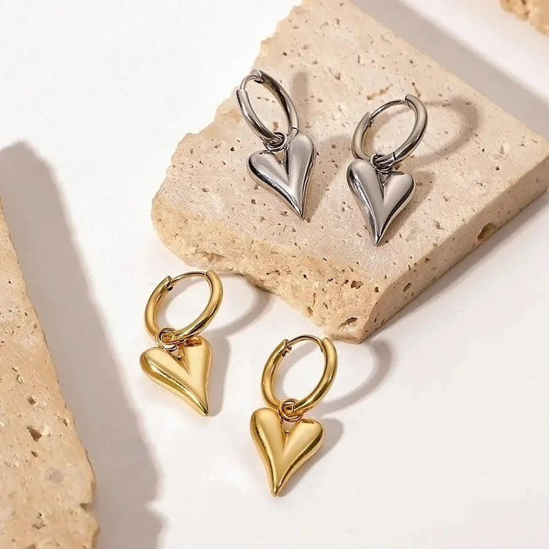 Chic Heart Hoop Earrings in gold and silver on textured surface, showcasing modern elegance and style for any occasion.