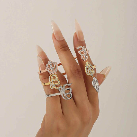 Hand wearing multiple rings with various designs on a neutral background