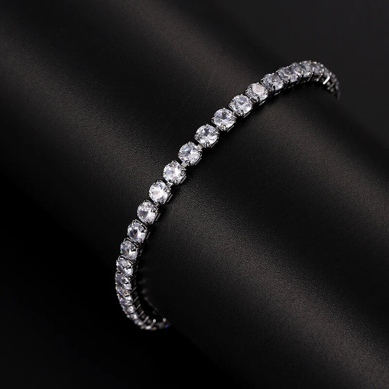 Silver iced out tennis bracelet with clear zirconia displayed on black cylinder, elegant hip hop accessory for men and women.