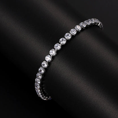 Silver iced out tennis bracelet with clear zirconia displayed on black cylinder, elegant hip hop accessory for men and women.