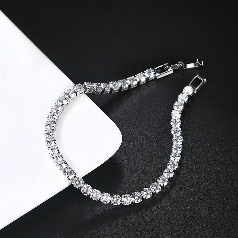 Open silver iced out tennis bracelet with clear zirconia on black and white background, modern hip hop jewelry design.