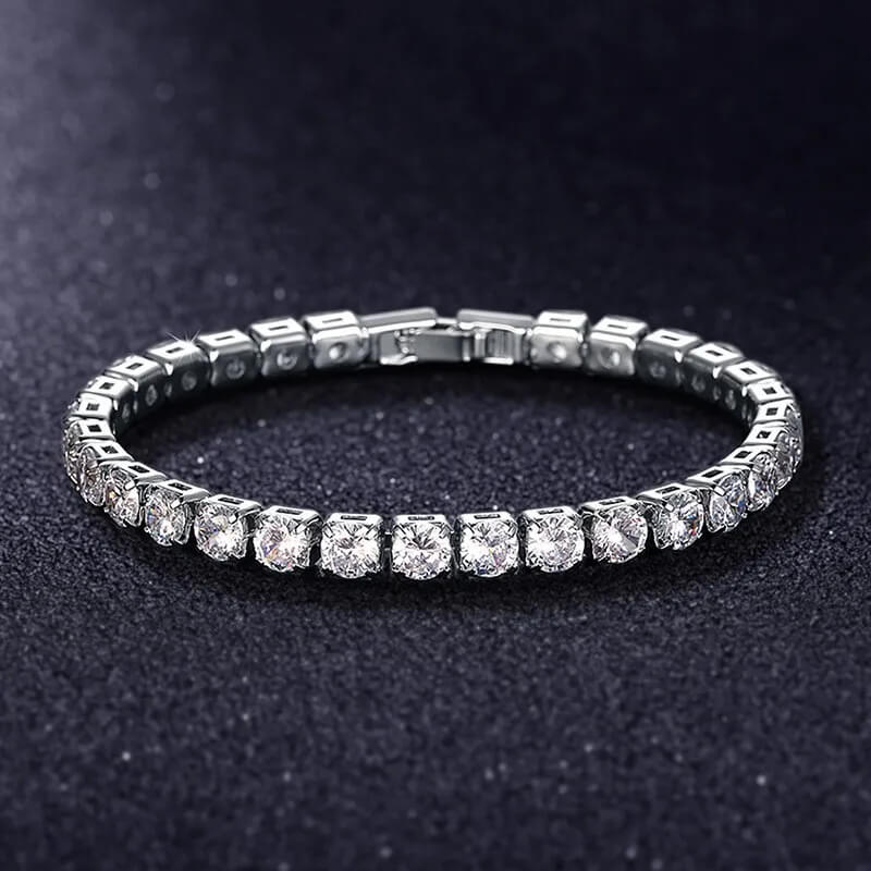 Silver iced out tennis bracelet with clear zirconia stones displayed on black background, luxury hip hop jewelry for men and women.