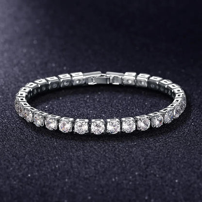 Silver iced out tennis bracelet with clear zirconia stones displayed on black background, luxury hip hop jewelry for men and women.