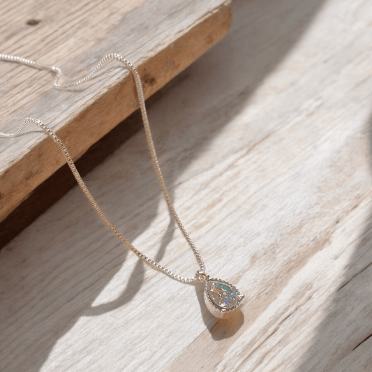 Tear Drop Zircon Necklace on wood, featuring a sparkling water drop zircon pendant and delicate box chain.