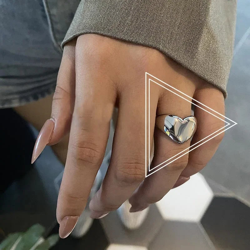 Close-up of a hand wearing a Lustrous Heart Ring in 925 sterling silver with 18K Gold Vermeil, showcasing its elegant design.